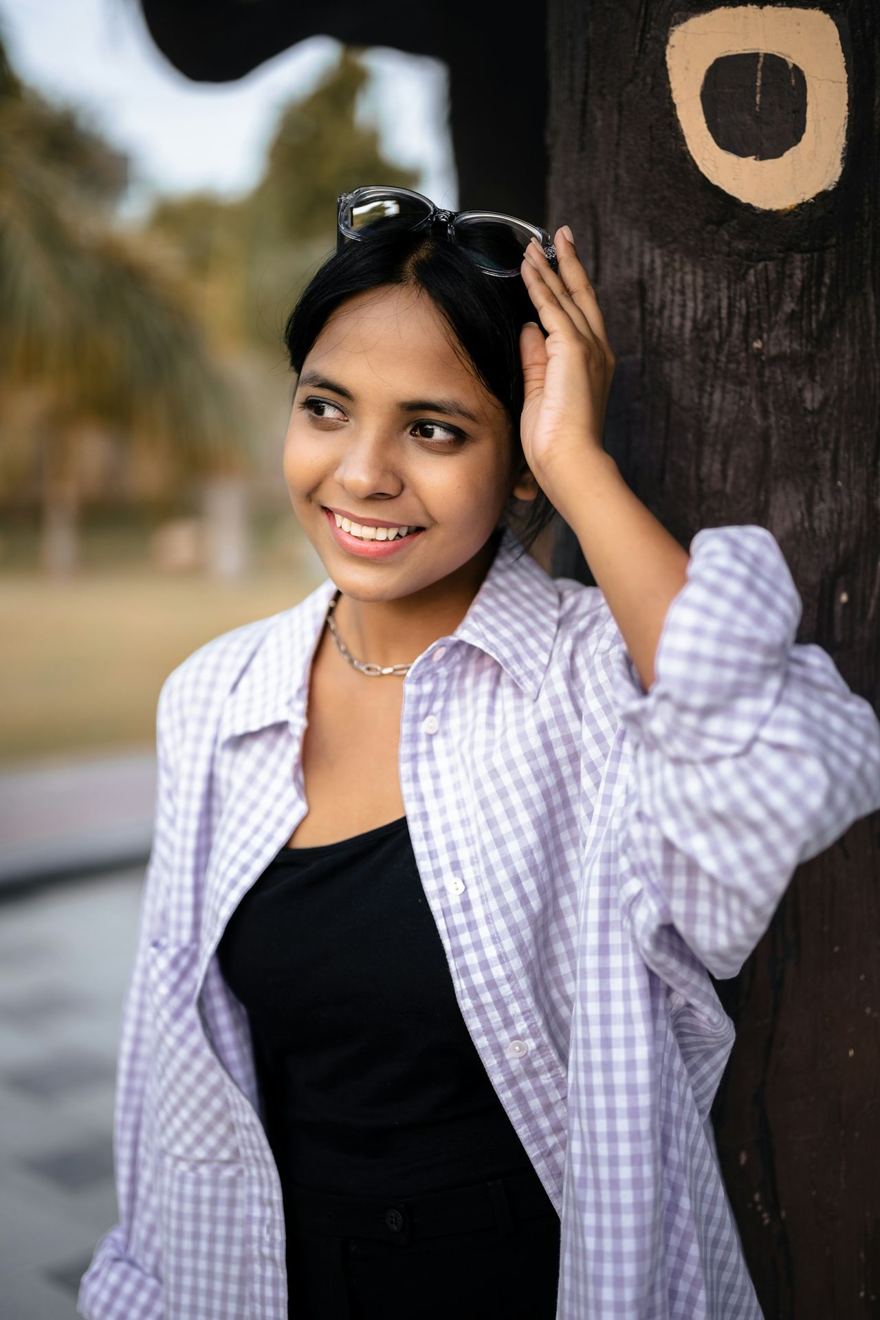 A woman is leaning against a wooden pole